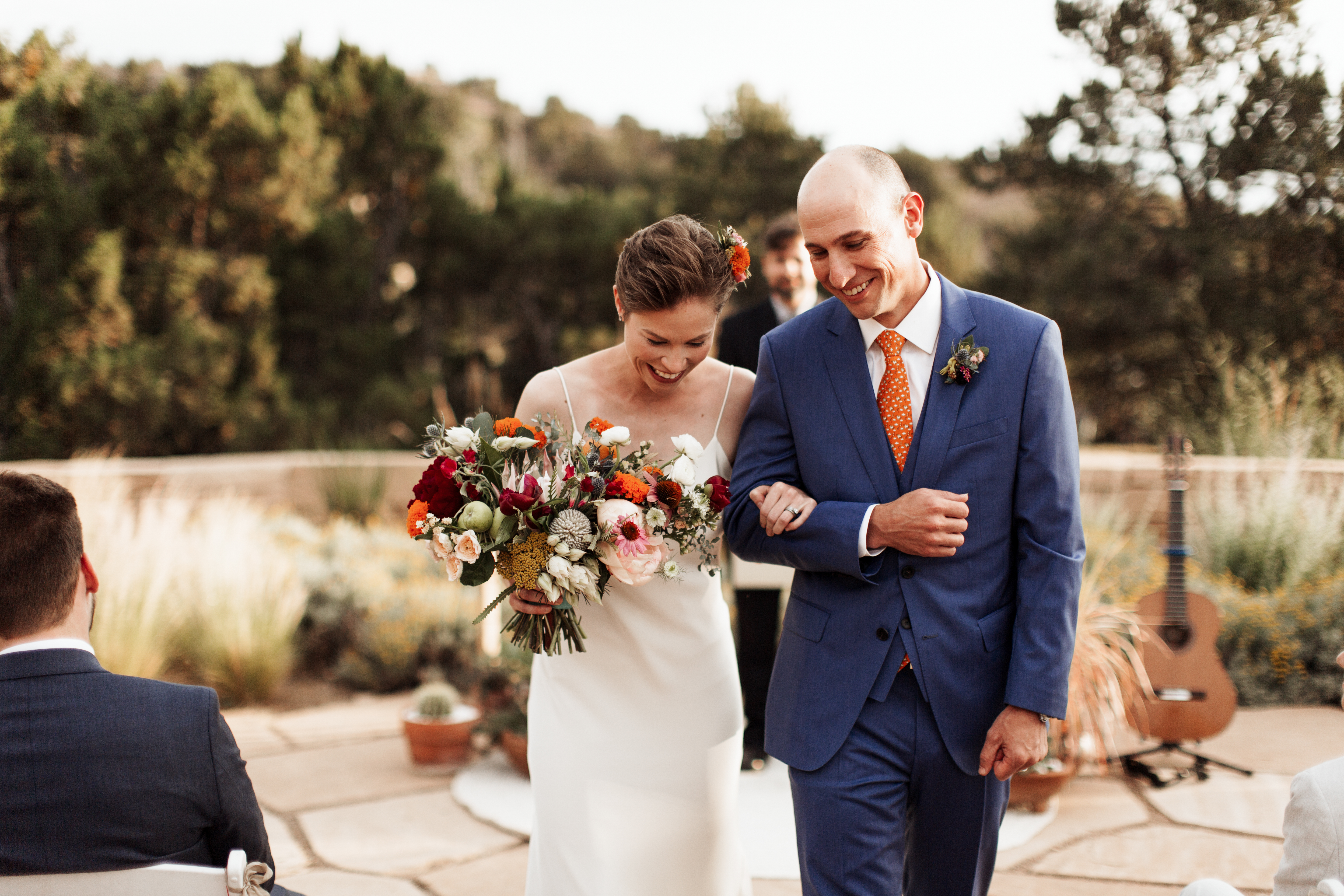 jewel tones wedding outdoor ceremony planning New Mexico design inspiration orange blue suit silk gown bouquet live music band vows officiants real hair bridal photography romantic couple natural light
