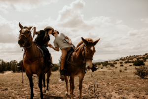 Engaged Colorado couple posing on horseback for Colorado engagement photo