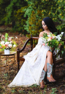 Bride holds bridal flowers while lounging outside on a bench.