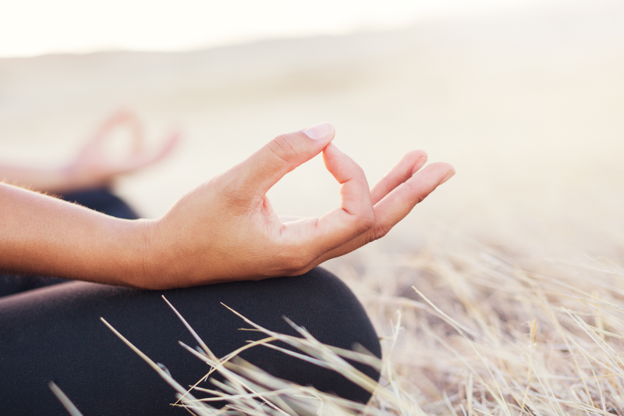 Bride to be meditating in a field.